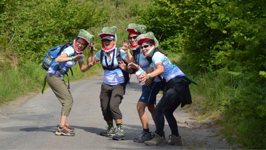 Four women hiking whilst dressed as dinosaurs