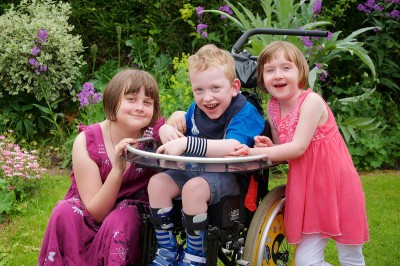 Tom, pictured centre in his wheelchair, with his two sisters